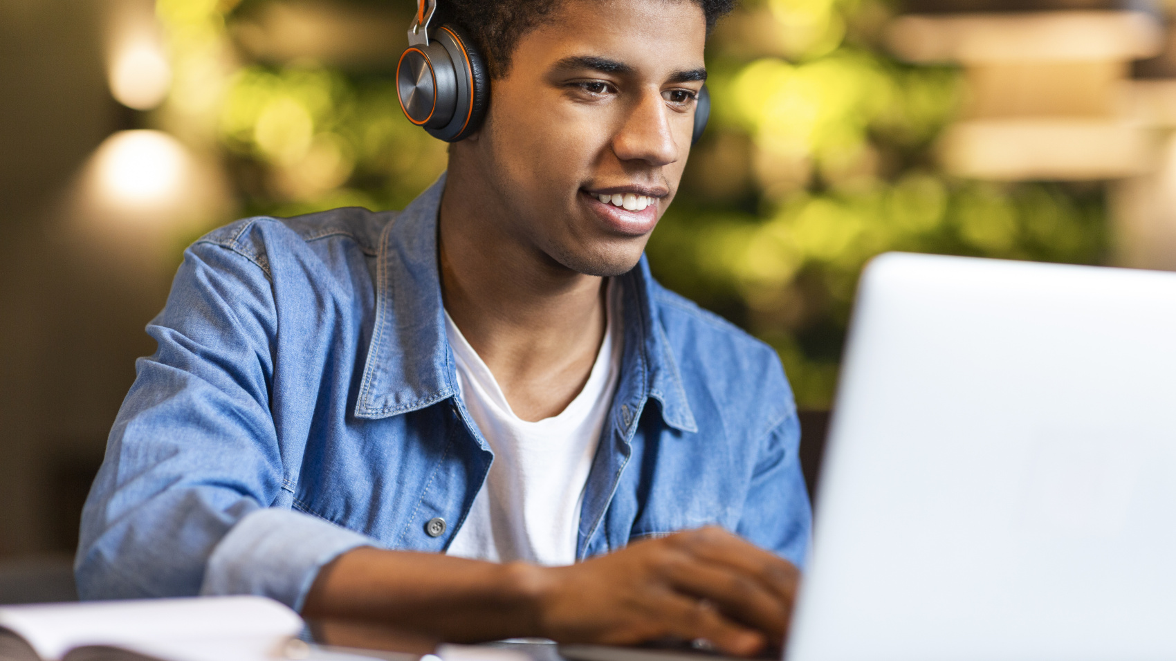 A young man listens to music as he works at his laptop